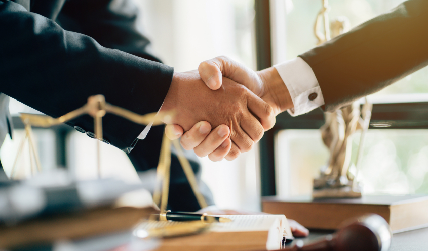 A corporate lawyer shakes hands with a business owner.