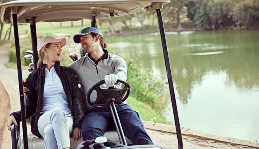 A couple riding on a golf cart together, illustrating people that may need a golf cart accident lawyer.