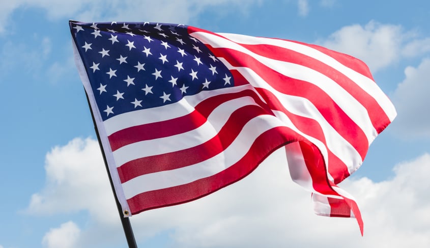 A picture of an American flag floating in the wind, displaying Plakas Mannos 4th of July tips.