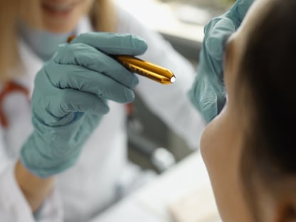 doctor holding a pen light up to a TBI patient's eye during exam