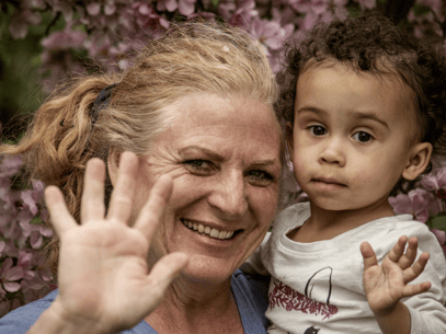 grandma waving at camera while holding grandson she won custody of via grandparents' rights