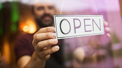 Shop owner turning over his open sign on a window