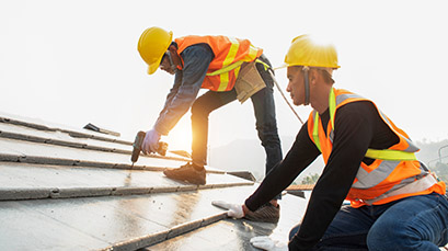 Two construction workers working on metal roofing